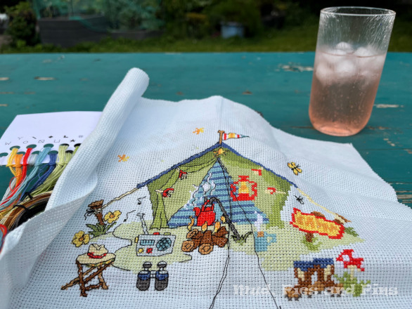 Backtstitching a cross stitch design of a text with an evening drink in the garden